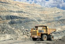 Grande caminhão amarelo de mineração em uma pedreira rochosa sob céu claro