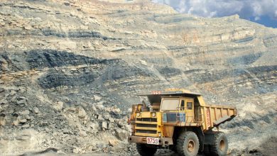 Grande caminhão amarelo de mineração em uma pedreira rochosa sob céu claro
