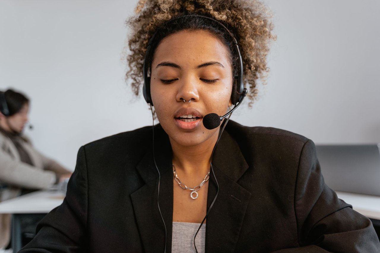 Atendente de serviço ao consumidor usa fones de ouvido em um ambiente profissional de atendimento.