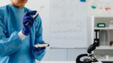 Cientista de jaleco examina amostras ao microscópio em um laboratório.