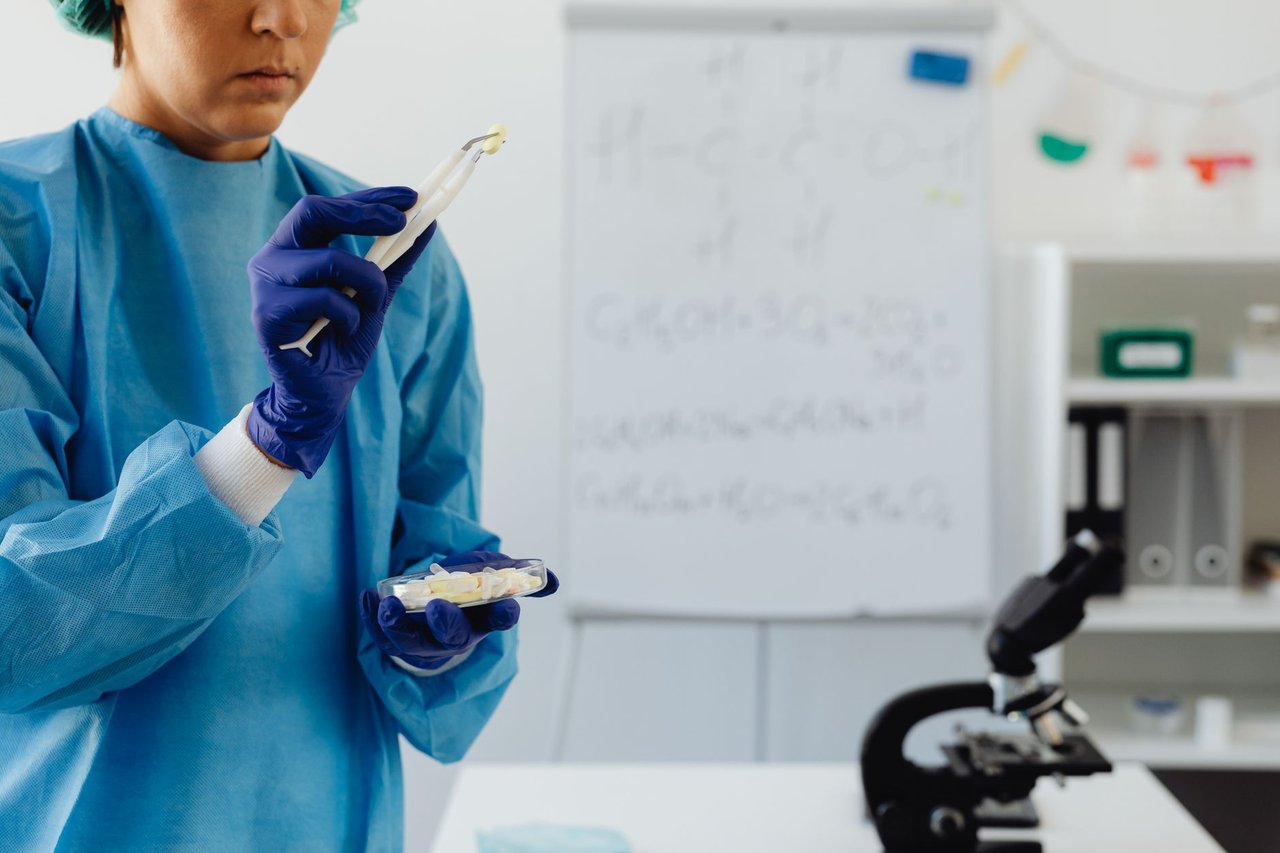 Cientista de jaleco examina amostras ao microscópio em um laboratório.